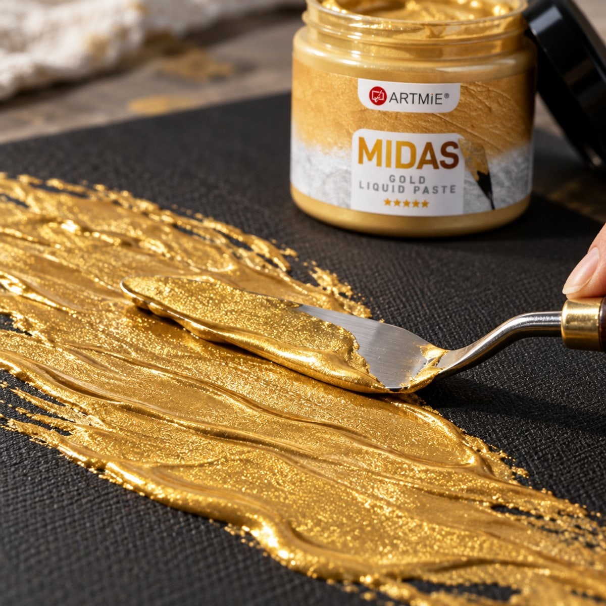 Aplicarea pastei metalice aurii ARTMIE MIDAS cu spatula pe pânză neagră — macro
